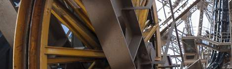 ...Au premier plan une roue jaune de machinerie d’ascenseur et au second plan en noir les guides d’ondes radio. Ces feeders sont des liaisons coaxiale reliant les antennes du somme de la Tour Eiffel à la station d’émission situé sous et à proximité de la tour....
