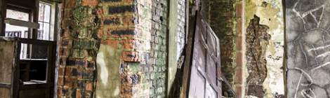 ...Bâtiment en friche avec moisissure sur les murs et porte défoncée...