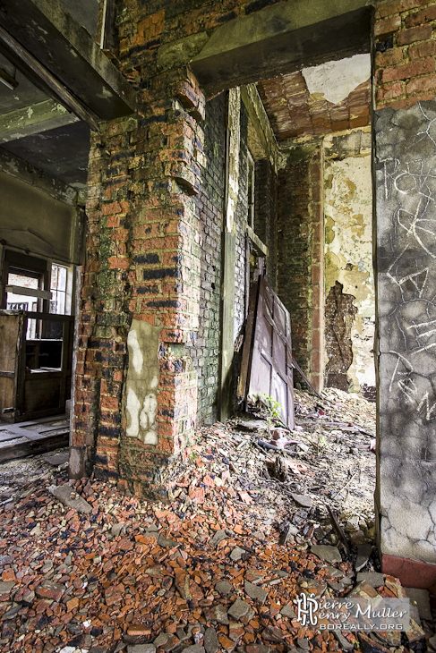 Bâtiment en friche avec moisissure sur les murs et porte défoncée