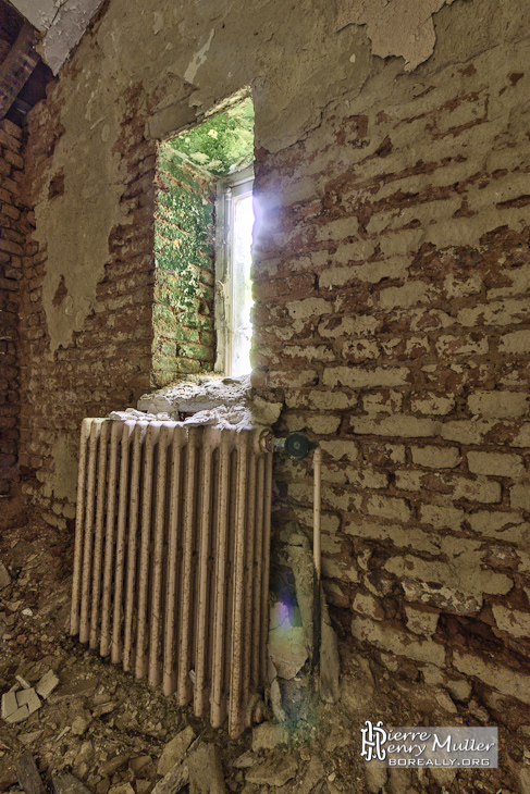 Pièce délabrée avec radiateur en fonte et fenêtre au château Noisy en HDR