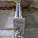 Sculpture d'un homme sous un pilier dans l'escalier du château de Noisy