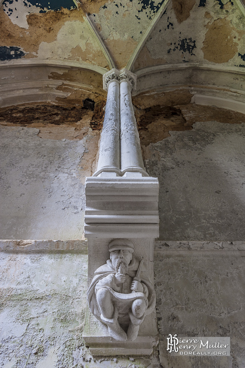 Sculpture d'un homme sous un pilier dans l'escalier du château de Noisy