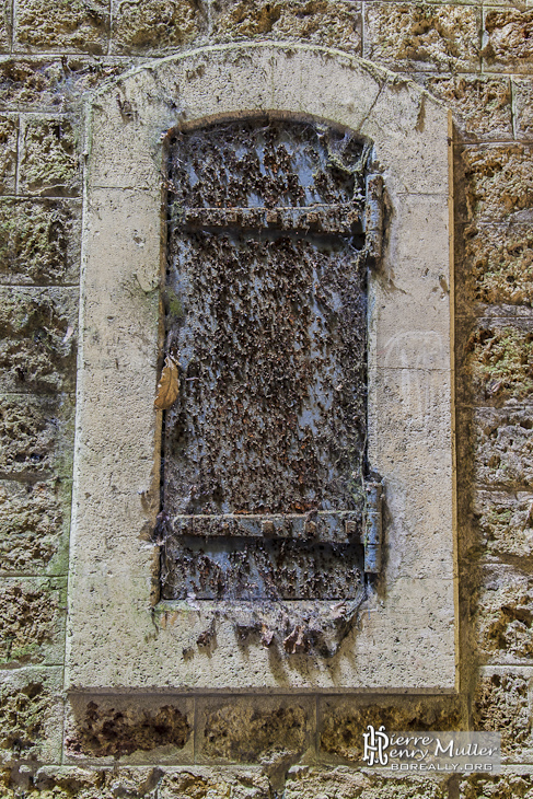 Fenêtre métallique rouillée de la poudrière du Fort du Haut Buc en vue portrait