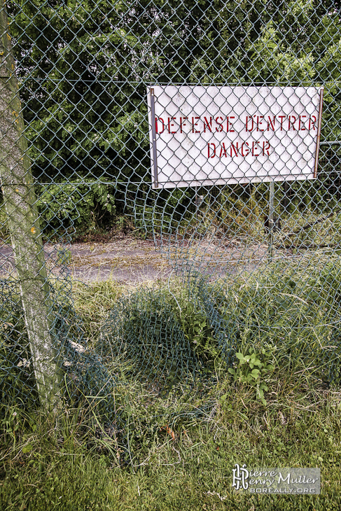 Trou dans l'enceinte grillagée avec panneau défense d'entrer danger