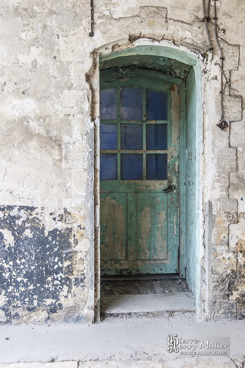 Porte en bois à la peinture écaillée au Fort du Trou d'Enfer