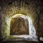 Sortie du tunnel fermée par une porte en bois laissant passer la lumière