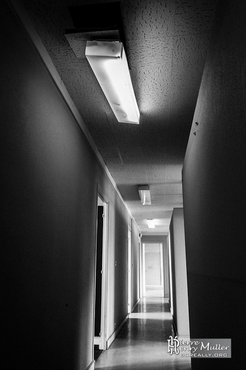 Photo noir et blanc d'un couloir éclairée aux néons de l'imprimerie abandonnée