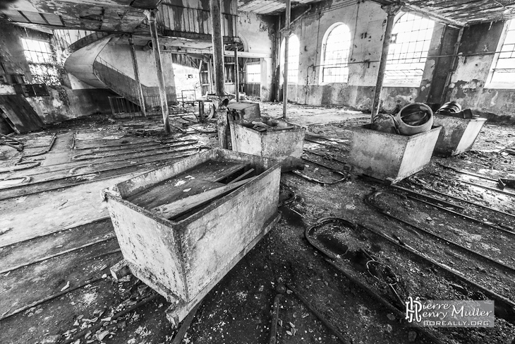 Berlines sur rails dans un hangar de la papeterie Darblay en noir et blanc