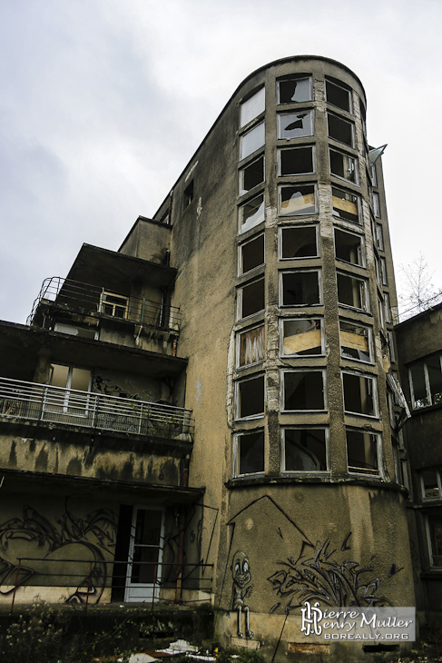 Cage d'escalier arrondie avec vitres carrées et les différents niveaux de balcons