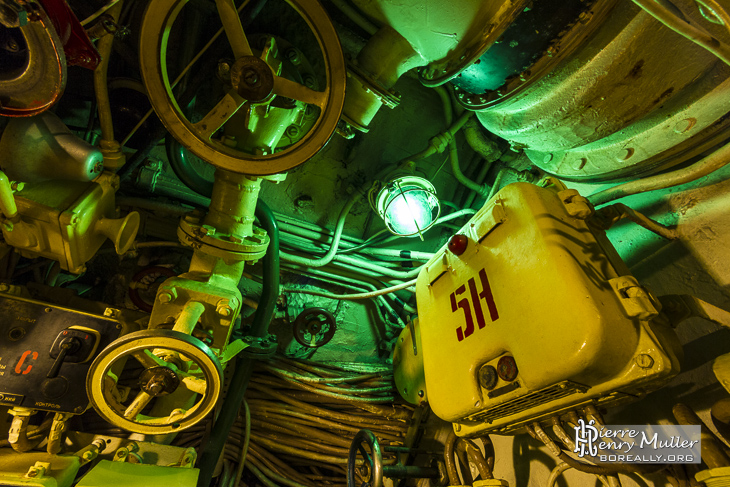 Lampe verte au milieu des câbles et vannes du sous-marin