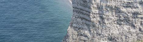 ...La plage et la ville d’Etretat vue depuis la porte d’Aval avec au premier plan des personnes sur le chemin des falaises....