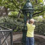 Enfant remplissant une gourde d'eau à la fontaine Wallace de la butte Montmatre