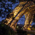 Pieds de la Tour Eiffel et reflet sur le plan d'eau de nuit