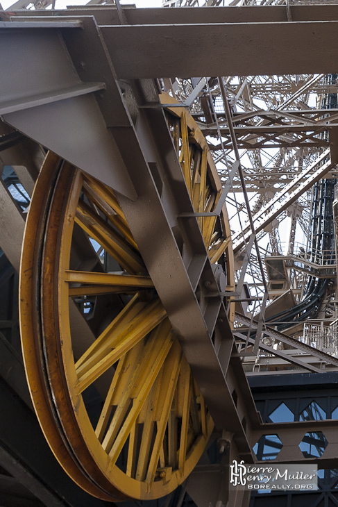 Roue jaune de machinerie d'ascenseur et guides d'ondes de la Tour Eiffel