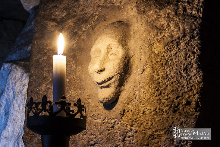 Visage modelé sur le mur de la carrière devant une bougie