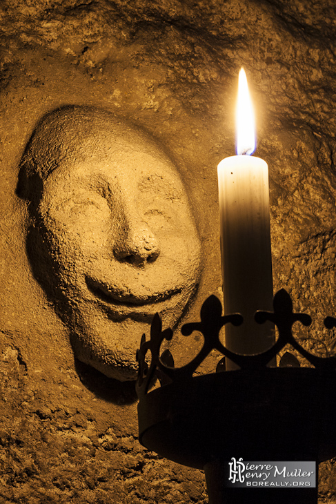 Visage souriant modelé au mur devant une bougie