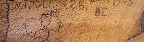 ...Dessin d’un bonhomme au noir animal sur un mur avec comme inscription Vossaert Napoléon et une date 25 avril 1903....