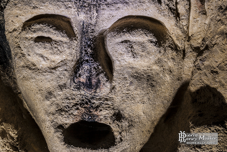 Sculpture d'un visage sur un mur de calcaire dans la carrière patate