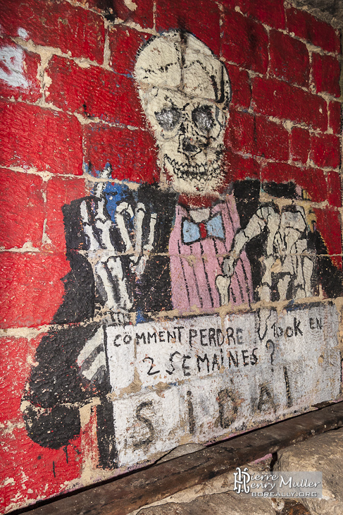 Squelette habillé d'un costume sur le mur des promotions des catacombes de Paris