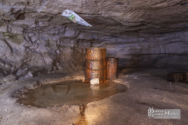 Bidons rouillés de collecte d'eau dans une carrière souterraine