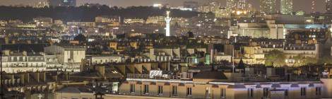 ...La colonne de la Bastille de nuit dépasse des toits parisien....
