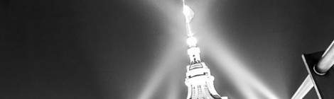 ...Dôme du Grand-Palais avec sa flèche au sommet de laquelle flotte le drapeau français abondamment éclairé par de puissant projecteur. Photographie en noir et blanc....