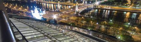 ...Toits de Paris de nuit depuis la verrière du Grand Palais éclairée avec vue sur le pont Alexandre III et les Invalides....
