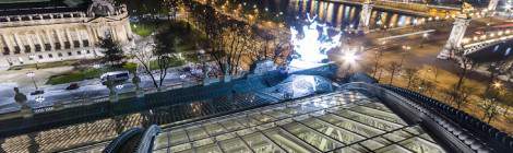 ...Vue sur la verrière du Grand-Palais éclairée, un quadrige Récipon, le Petit-Palais à gauche, le pont Alexandre III à droite et la Seine sur un fond des toits de Paris la nuit....