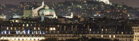 ...Vue panoramique de nuit sur les toits de Paris avec vue sur les immeubles de la rue de Rivoli, l’Opéra Garnier et le Sacré Coeur....