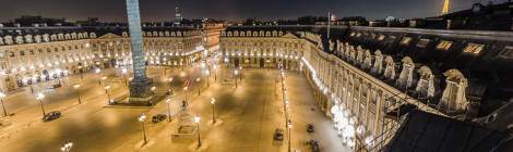 ...La place Vendôme, sa colonne et ses bâtiments haussmanniens et la Tour Eiffel de nuit depuis les toits de Paris....