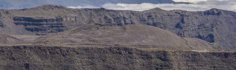 ...Depuis le sommet du Piton de la Fournaise, vue sur l’enclos Fouqué, le pas de Bellecombe et son parking sur la droite, la plaine des sables et au loin le Piton des Neiges....