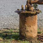 Canalisation rouillée sortant de terre dans une installation pétrolière