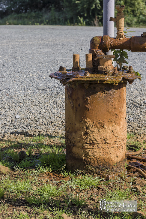 Canalisation rouillée sortant de terre dans une installation pétrolière